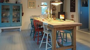 En matplats med ett träbord, färgglada stolar, en spis och ett blått skåp.
