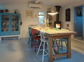 A dining area with a wooden table, colorful chairs, a stove, and a blue cabinet. - Personal house with direct access to the beach (Sjællands Odde)