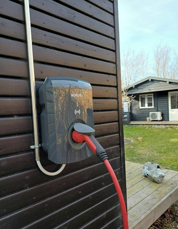 A Norlys electric vehicle charging station attached to a wooden wall. - Personal house with direct access to the beach (Sjællands Odde)