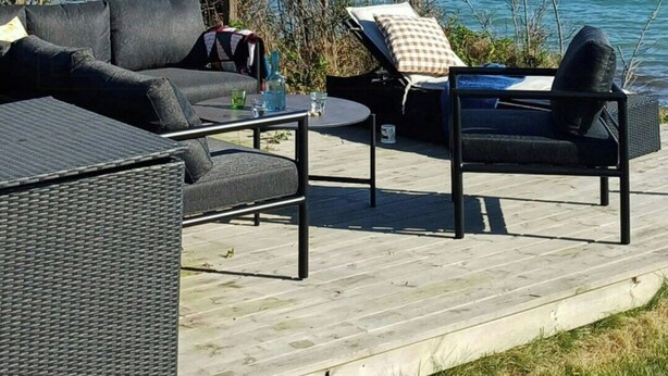 En terrass med utemöbler, ett bord och utsikt över havet.