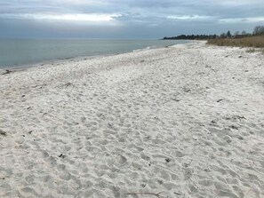 A sandy beach with a calm sea and overcast sky. - Architect-designed wooden house near beach (Odder)