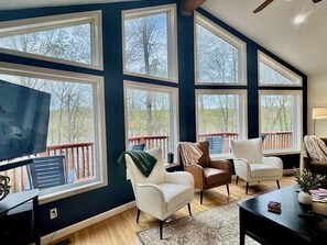 A spacious living room with large windows, a television, and multiple seating areas. - Zen at Marker 10~ Lakefront Home with Hot Tub! (Pittsville)