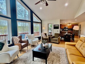 A spacious living room with a large window, a ceiling fan, and a view of the outdoors. - Zen at Marker 10~ Lakefront Home with Hot Tub! (Pittsville)