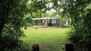 A wooden cabin with a covered porch and a grassy yard. - Cottage life in intimate wooden cabin (Dronningmølle)