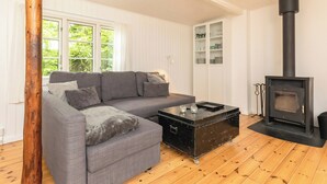 A living room with a sofa, a coffee table, a fireplace, and a wooden floor. - Cottage life in intimate wooden cabin (Dronningmølle)