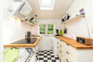 A compact kitchen with a central island, a washing machine, and a window with a view of greenery.