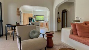 A modern living room with a sofa, armchair, and coffee table. A kitchen is visible in the background. - Ibiza-style villa in Jávea near beach with pool (Jávea)