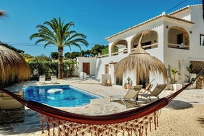 Ein Pool mit Liegestühlen, einer Hängematte und einem Gebäude mit Bögen.