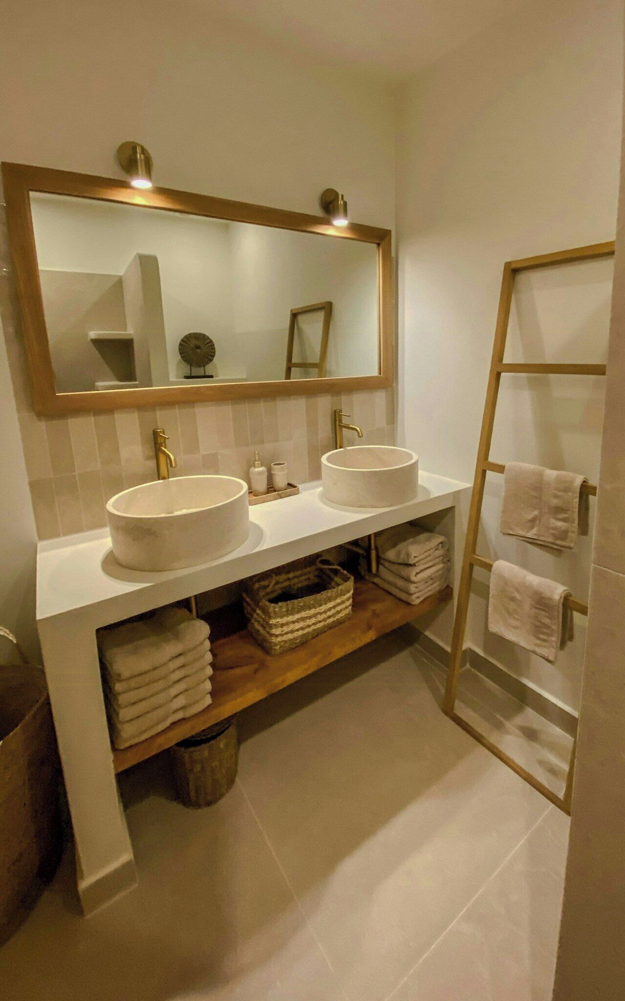Un baño con dos lavamanos, un espejo grande y un perchero para toallas.