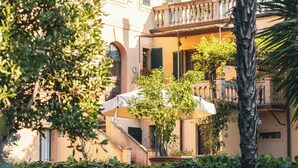 Un edificio con un balcone e un giardino pieno di fiori rossi.