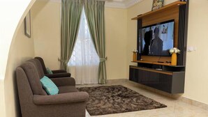 A living room with a sofa, TV, and a decorative vase.