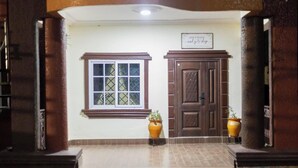 A room with a window, a door, and two potted plants.