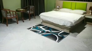 A bedroom with a bed, a chair, a desk, a nightstand, and a painting on the wall. - Modern 3BR Luxury Diamond Hills Residency (Kumasi)