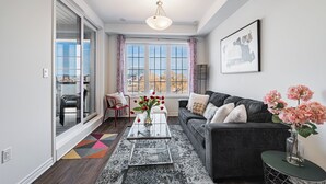 Een moderne woonkamer met een bank, een bijzettafeltje en een uitzicht door grote ramen.