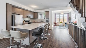 Een moderne keuken met een centraal eiland, barkrukken en een eethoek met uitzicht.
