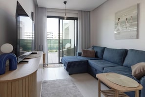 Ein modernes Wohnzimmer mit Sofa, Couchtisch, Fernseher und Balkon mit Blick.