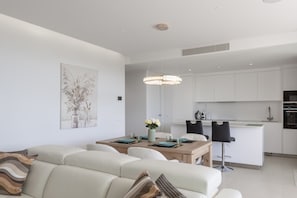 Ein modernes Wohnzimmer mit Sofa, Esstisch und Küchenzeile.