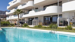 A modern hotel with a swimming pool, multiple balconies, and a view of the mountains. - Exclusive Garden Suite in Higueron (Fuengirola)