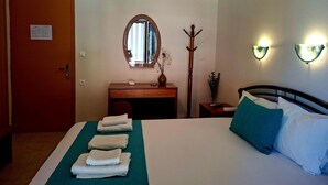 Een hotelkamer met een bed, een houten dressoir, een kapstok en twee wandlampen.