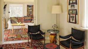 A living room with a sofa, two chairs, a lamp, a small table, and a patterned rug.