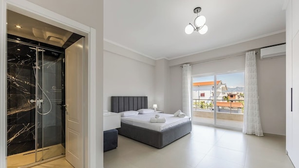 A modern bedroom with a bed, bedside table, and a glass-enclosed shower.