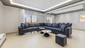 A modern living room with a large L-shaped sectional sofa, a round coffee table, and a small ottoman.