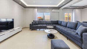 A modern living room with a sectional sofa, a flat-screen TV, a coffee table, and a TV stand.