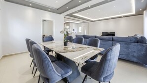 A modern dining area with a marble table, blue chairs, and a grey sofa.