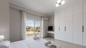 A hotel room with a bed, a TV, a wardrobe, and a balcony with a view.