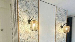 Un dormitorio con cama, dos lámparas de pared, papel tapiz estampado y una ventana con cortinas.