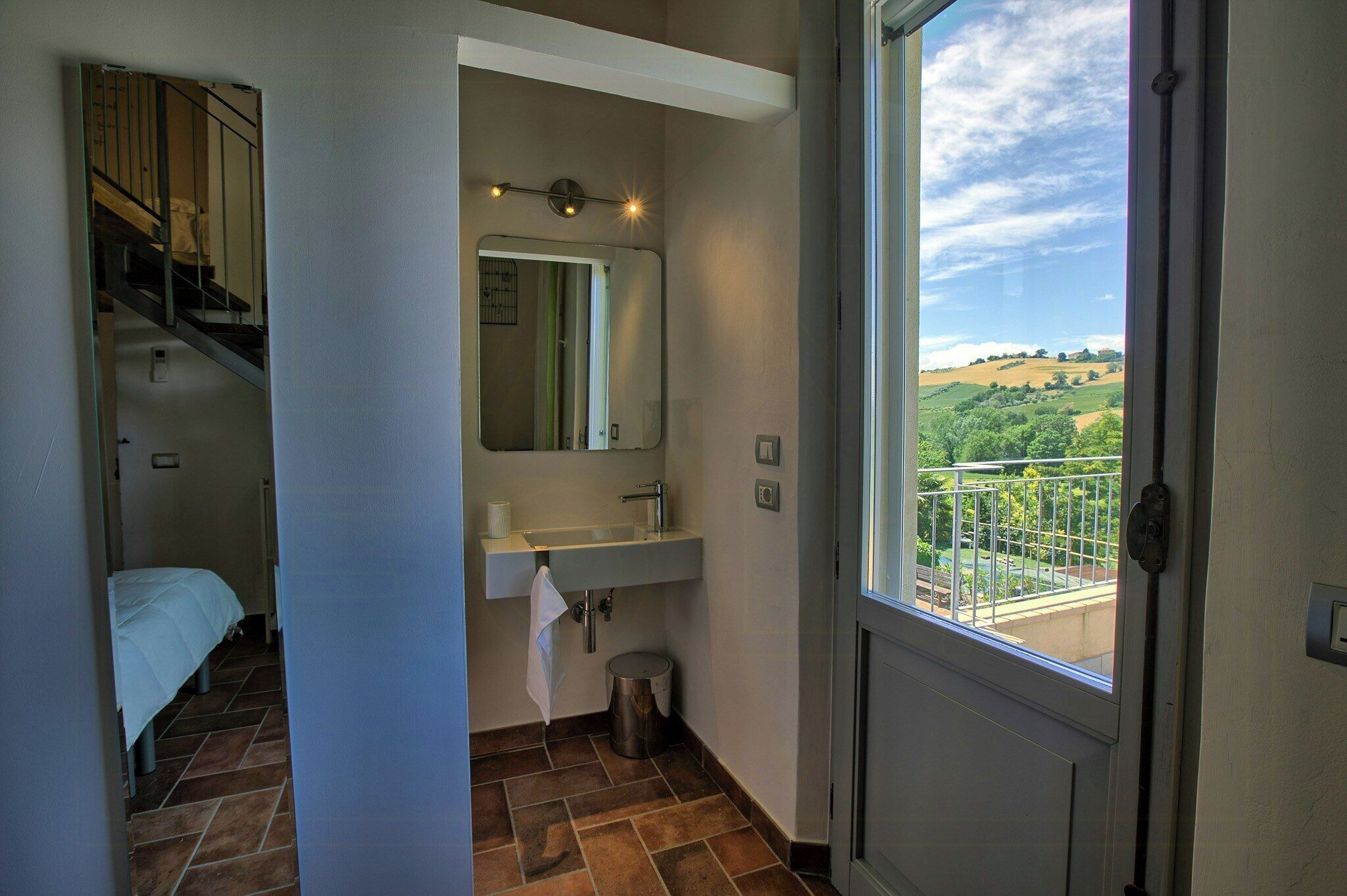 Une salle de bain avec un lavabo, un miroir et une fenêtre.