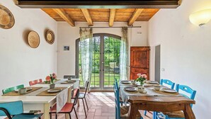 Un comedor con mesas y sillas de madera, un ventanal con cortinas y vistas al exterior.