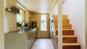 Une cuisine étroite avec un escalier en bois menant à un niveau supérieur.
