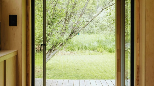 Un intérieur en bois avec une porte coulissante donnant sur une terrasse extérieure.