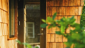 Une maison en bois avec une porte, une fenêtre et une paire de bottes sur le porche.