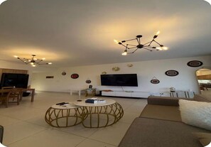 Ein modernes Wohnzimmer mit einer Couch, zwei runden Couchtischen, einem Fernseher und Wandbildern.