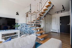 A modern living room with a staircase, a flat-screen TV, and a patterned wall. - Komfortowy dom nad morzem (Jastrzębia Góra)