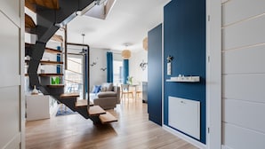 A modern interior with a staircase, wooden flooring, a blue accent wall, and a dining area with a table and chairs. - New holiday home by the sea (Jastrzębia Góra)