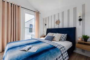 A modern bedroom with a large bed, striped wall decor, and a view of the outside.