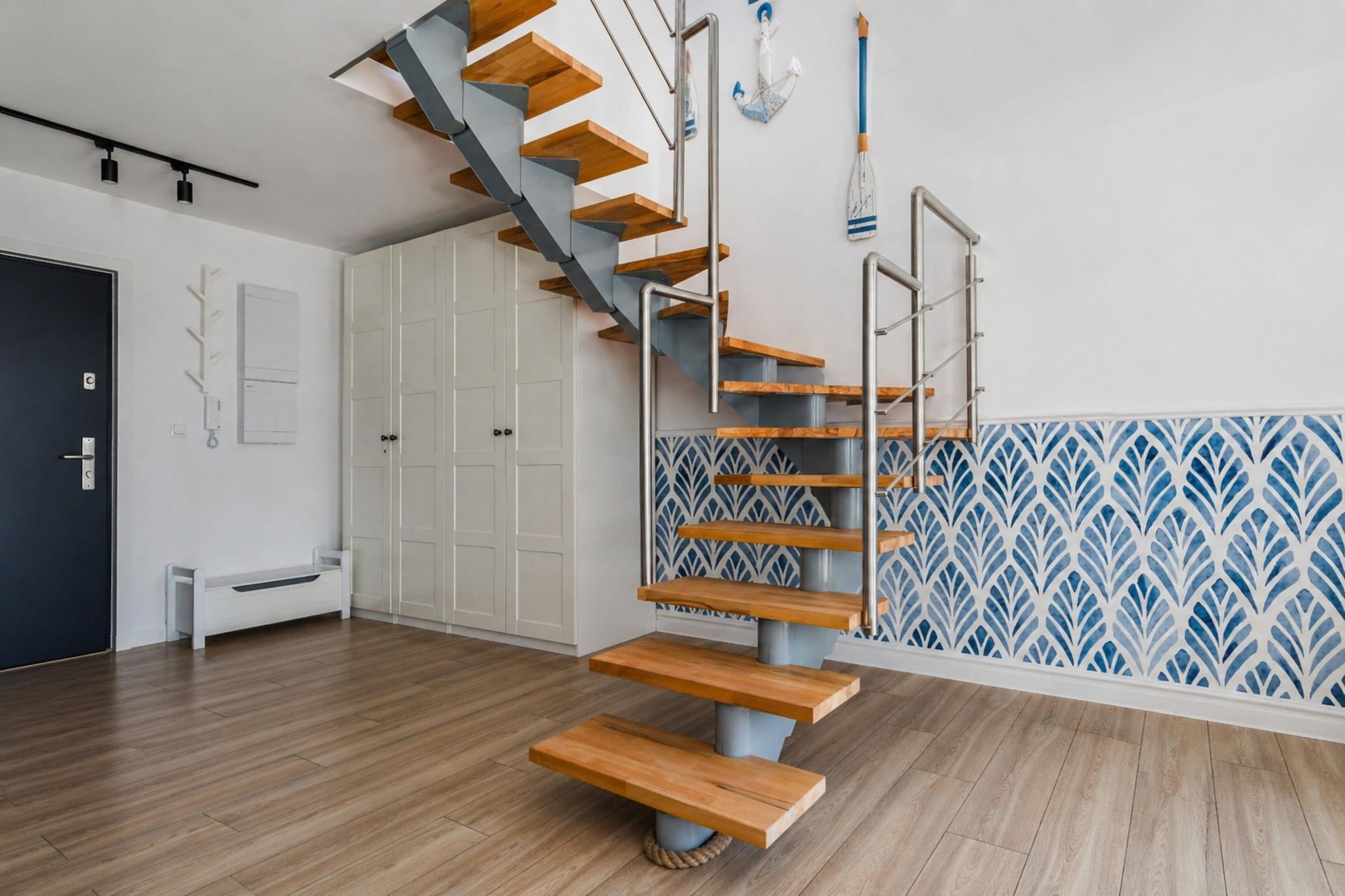 Un intérieur moderne avec un escalier en bois, des armoires blanches et des carreaux muraux à motifs.