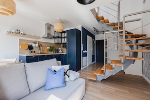 Une cuisine moderne avec des étagères en bois, un coin repas avec un canapé et un escalier.