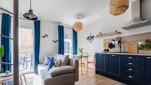 A modern living room with a sofa, dining table, and kitchen area with cabinets and a hanging light fixture. - New holiday home by the sea (Jastrzębia Góra)