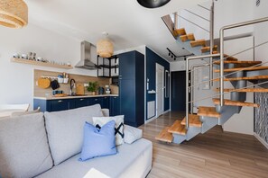 A modern kitchen with wooden cabinets, a built-in stove, and a hanging light fixture.