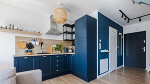 A modern kitchen with blue cabinets, wooden countertops, and a hanging light fixture. - New holiday home by the sea (Jastrzębia Góra)