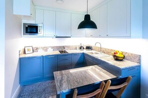 Une cuisine compacte équipée d’un four à micro-ondes, d’un évier et d’un petit coin repas avec des chaises.