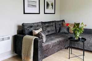A modern living room with a dark grey sofa, a small side table, and a radiator.