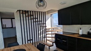Une cuisine moderne avec des meubles de rangement noirs, une table à manger en bois et une chaise noire.