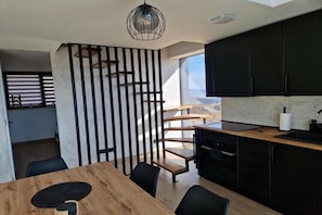 A modern kitchen with black cabinets, a wooden dining table, and a black chair.