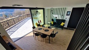 Un intérieur moderne comprenant un coin repas, un canapé et une vue dégagée sur l’extérieur grâce à une grande fenêtre.