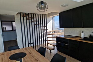 Eine moderne Küche mit schwarzen Schränken, einem Holzes Esstisch und einer Wendeltreppe.
